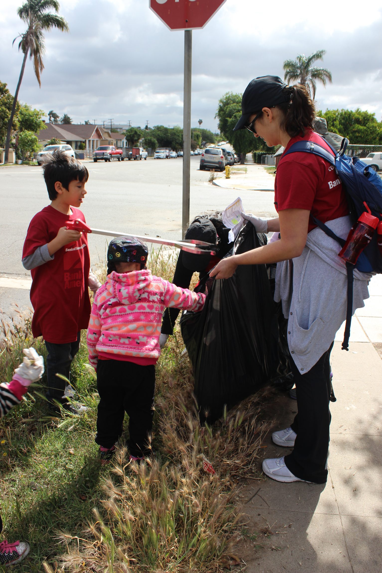 A family with the Bank of America volunteer team at Memorial Community Park works together to clean up Logan Heights.